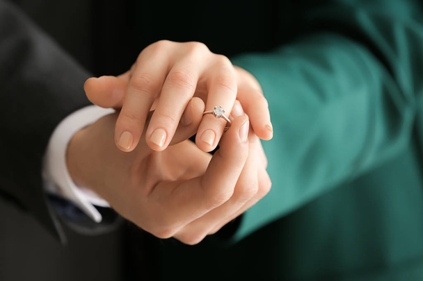 Young man putting engagement ring on fiancee's finger, closeup - Фото, изображение