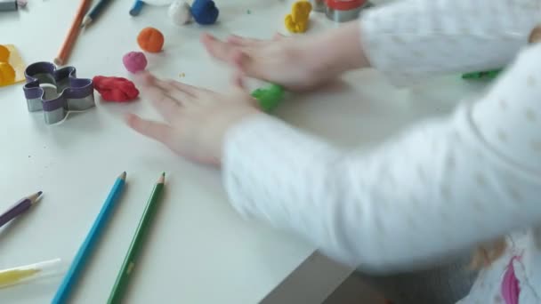 egy kis lány játszik a gyurmát, tekercs labdák, ábrák és a színes ceruza, az asztalon, a kezek finom motoros készségek fejlesztése - Felvétel, videó