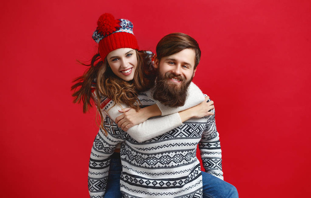 幸せな陽気なカップルの男と女で赤い背景があるのクリスマス帽子 - 写真・画像