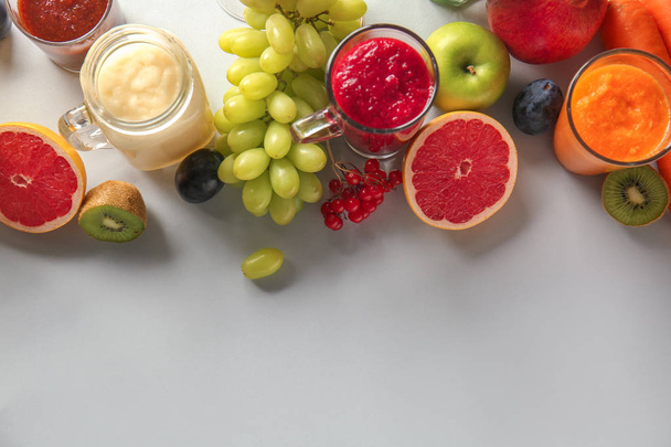 Glassware of tasty colorful smoothies with ingredients on light table - Photo, Image