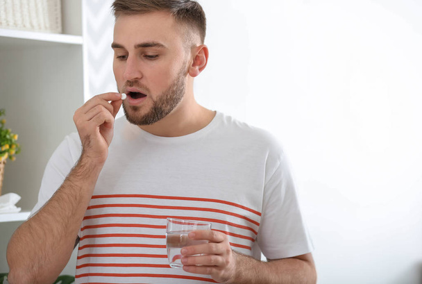 Mladý muž nemocný s chřipkou, který užívá léky doma - Fotografie, Obrázek