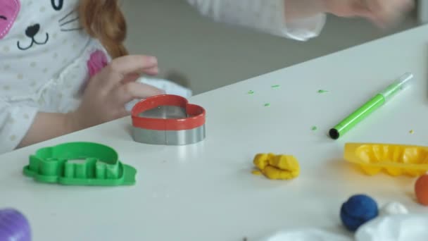 egy kis lány játszik a gyurmát, tekercs labdák, ábrák és a színes ceruza, az asztalon, a kezek finom motoros készségek fejlesztése - Felvétel, videó