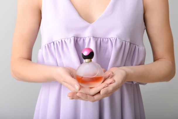 Woman with bottle of perfume on grey background, closeup - Photo, Image