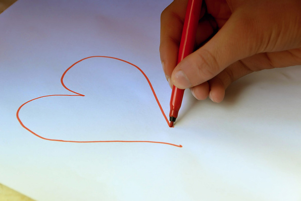 een jong meisje schildert een hart - Foto, afbeelding