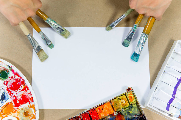 several paintbrushes with paint on a table - 写真・画像