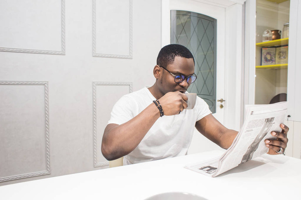 Young African American businessman reading a newspaper at breakfast. - Fotoğraf, Görsel