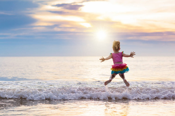 Child playing on ocean beach. Kid at sunset sea. - Foto, Imagen
