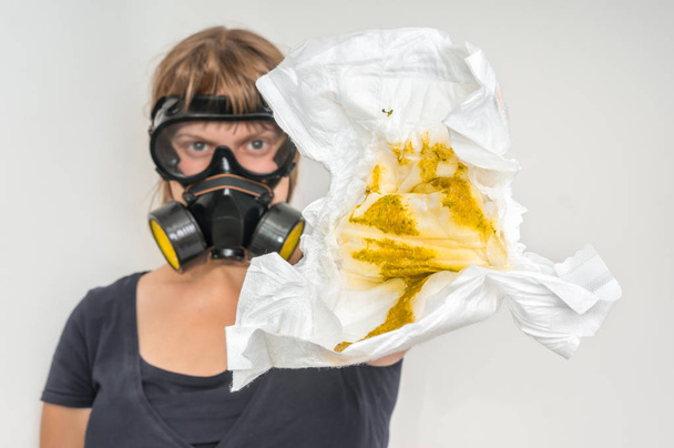 Mother with gas mask changing smelly diaper - baby care concept - Photo, Image