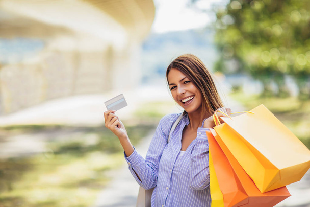 Young beautiful woman holding shopping bags and a credit card - Photo, Image