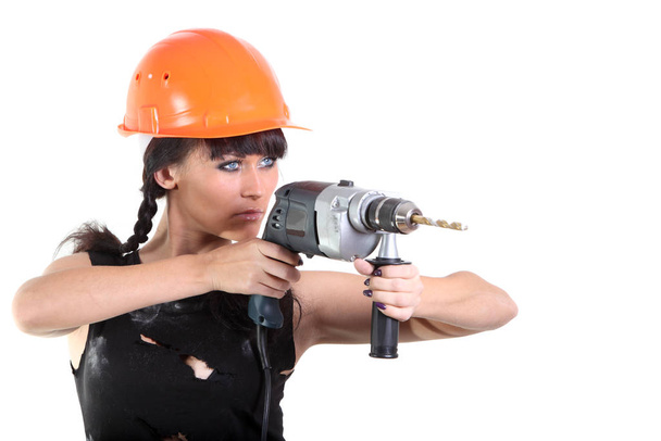 Girl in an orange hard hat holding a drill - Zdjęcie, obraz