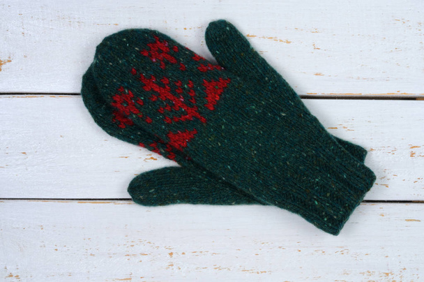 Knitted mittens in green on a white wooden background. Handwork. View from above. - Photo, Image
