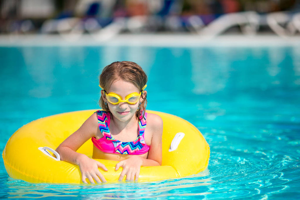 Menina pequena com círculo de borracha inflável que se diverte na piscina
 - Foto, Imagem