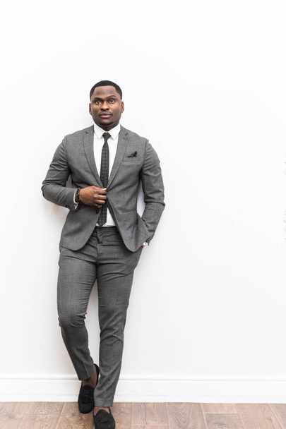 Joven empresario afroamericano en traje gris sobre fondo blanco
. - Foto, imagen