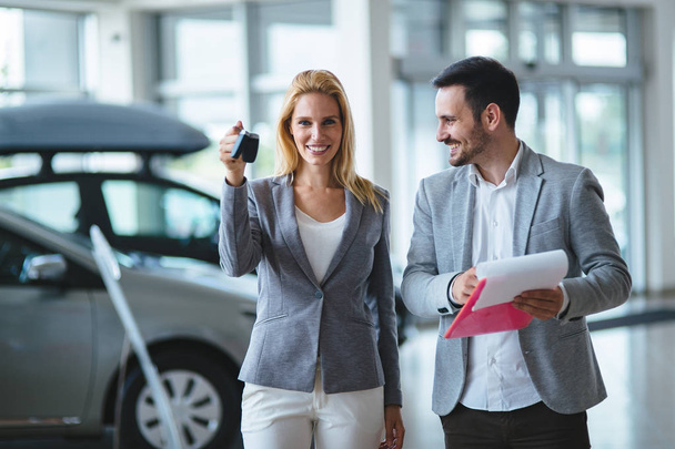 Professional salesperson selling cars at dealership to new buyer - Фото, изображение