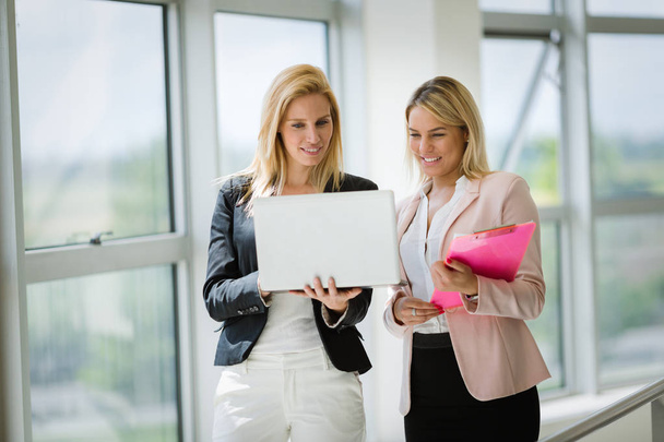 Happy young businesswomen doing paperwork in bright office - Photo, image