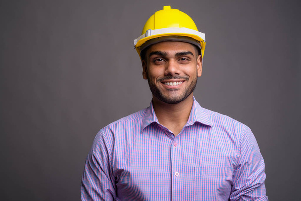 Mladý pohledný indický podnikatel nosit bezpečnostní přilba proti šedá b - Fotografie, Obrázek