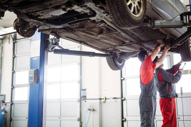 Car mechanics working at automotive service center together - Photo, image