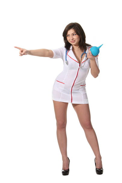 Young attractive nurse holding  enema and pointing  left - Photo, Image