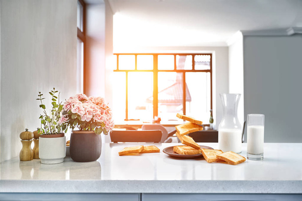 Tafel geserveerd voor het ontbijt met toast, melk en honing, op onscherpe achtergrond. Zon flare - Foto, afbeelding
