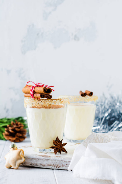 Eggnog Traditional Christmas drink milkshake with cinnamon on light old background. Selective focus. - Photo, Image