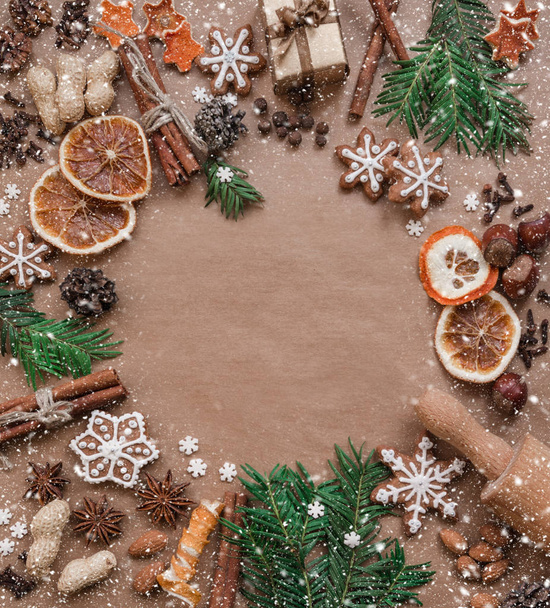 Frame with fir branches, cookies and Christmas decorations on dark brown paper background. Top view. - Fotó, kép