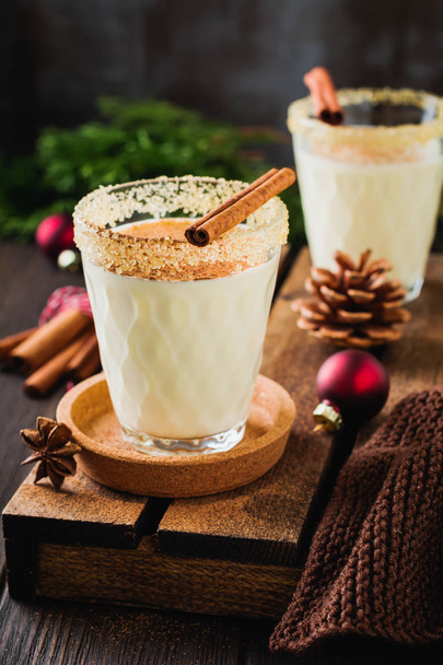 Eggnog Traditional Christmas drink milkshake with cinnamon on dark old background. Selective focus. - Foto, imagen