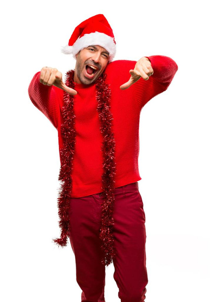 Man met rode kleren vieren de kerstvakantie aan te wijzen met de vinger naar iemand en veel lachen op geïsoleerde witte achtergrond - Foto, afbeelding