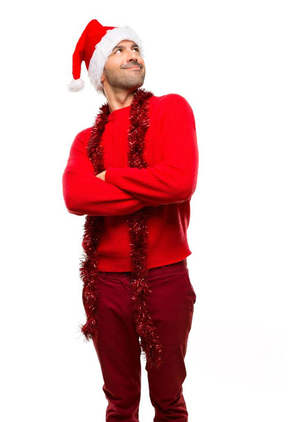 Mann mit roter Kleidung feiert die Weihnachtsfeiertage und blickt auf, während er auf isoliertem weißem Hintergrund lächelt - Foto, Bild