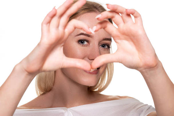 portrait jeune femme souriante faisant signe de coeur avec les mains - Photo, image