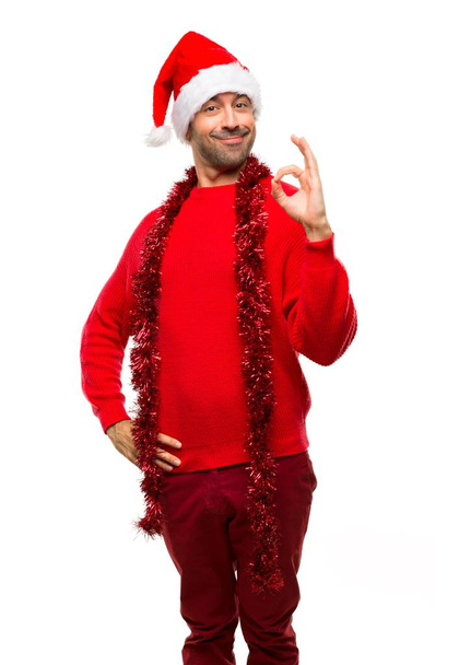 Homem com roupas vermelhas comemorando as férias de Natal mostrando um sinal ok com os dedos no fundo branco isolado
 - Foto, Imagem