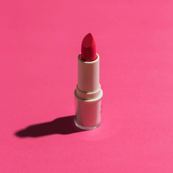 Brand new red tinted lipstick in studio light flat lay on pink background. - Zdjęcie, obraz