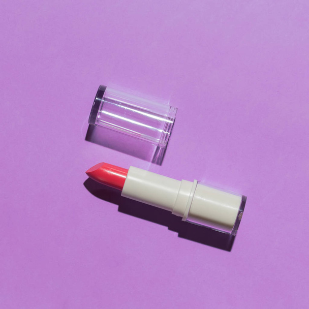 Opened red tinted lipstick in studio light flat lay on purple background. - Fotografie, Obrázek
