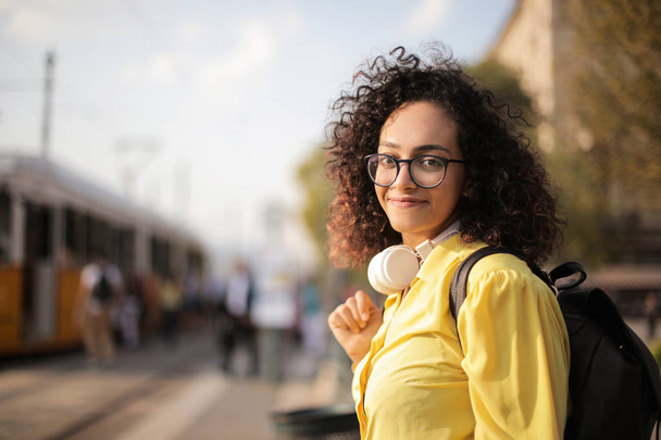 young black smiling girl with headphones in yellow shirt in the street - Foto, Imagen