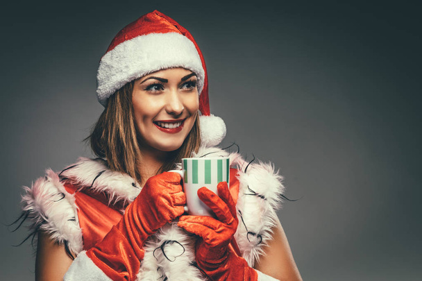 Muotokuva nuori hymyilevä nainen Santa Claus puku tilalla kuppi kuumaa teetä
 - Valokuva, kuva