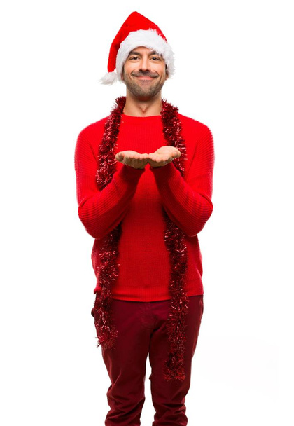 Homme avec des vêtements rouges célébrant les vacances de Noël tenant copyspace imaginaire sur la paume pour insérer une annonce sur fond blanc isolé
 - Photo, image