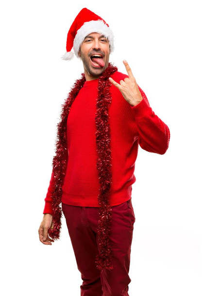 Homem com roupas vermelhas comemorando as férias de Natal mostrando a língua e tirando os chifres no fundo branco isolado
 - Foto, Imagem