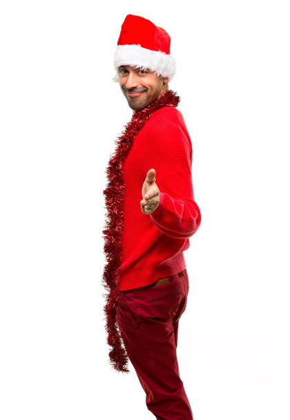 Man with red clothes celebrating the Christmas holidays handshaking after good deal on isolated white background - Photo, Image