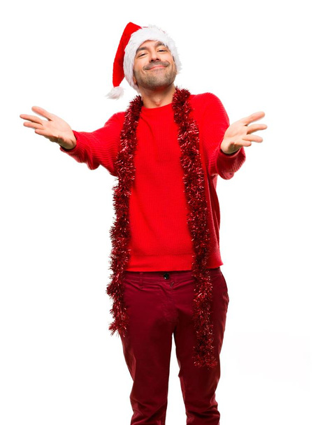 Homem com roupas vermelhas comemorando as férias de Natal apresentando e convidando para vir com a mão sobre fundo branco isolado
 - Foto, Imagem