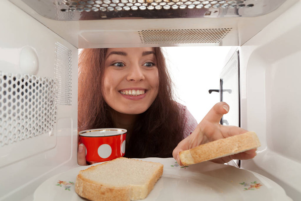 Attractive girl taking tost from a microwave - Foto, afbeelding
