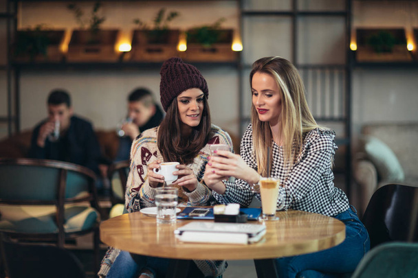 zwei Freunde genießen Kaffee zusammen in einem Coffeeshop und telefonieren - Foto, Bild