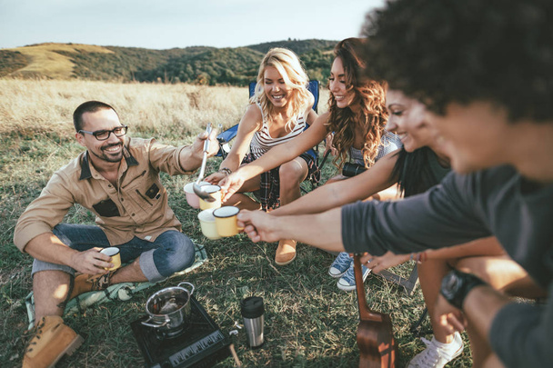 Grupo de jóvenes amigos divirtiéndose y relajándose en el picnic en el paisaje salvaje
  - Foto, Imagen