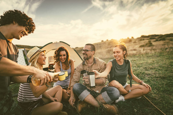 Groep jonge vrienden goede tijd doorbrengen op picknick in wild landschap  - Foto, afbeelding