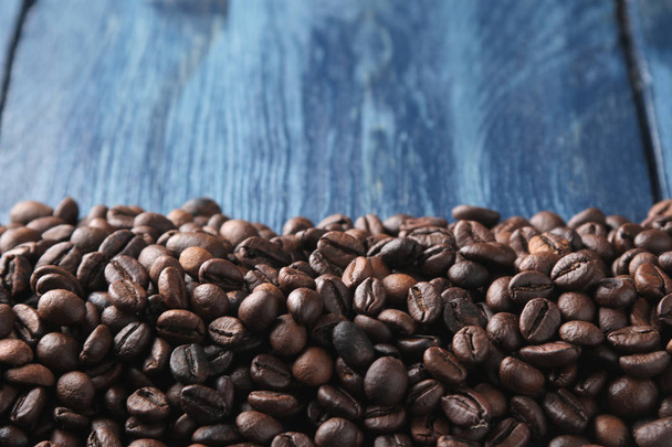 Marco de granos de café tostados en una mesa de madera azul. espacio para texto
 - Foto, imagen