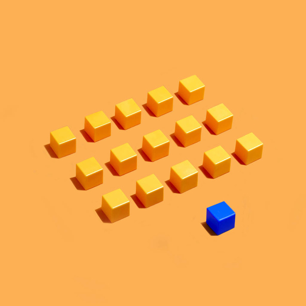 Rows of yellow cubes and blue in front on yellow background. Minimal style. Symbolic concept of leadership, individuality, difference from others - Photo, Image