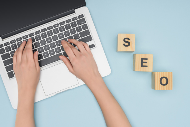 Top view of seo manager typing on laptop keyboard on light blue background  - Photo, Image