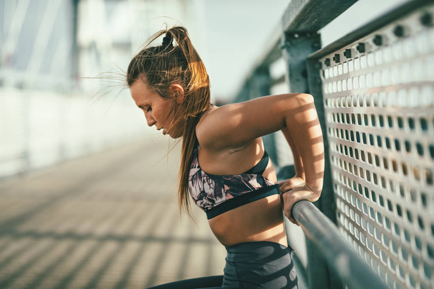 Young fitness woman doing hard exercise on river bridge - Photo, Image
