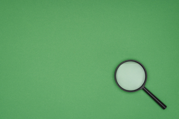Top view of magnifying glass on green background  - Photo, Image