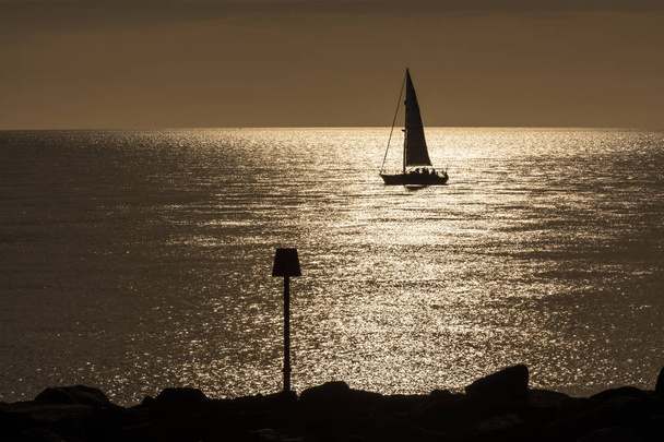Silhouette eines Segelschiffs bei Sonnenuntergang am Strand mit Bake, England. - Foto, Bild
