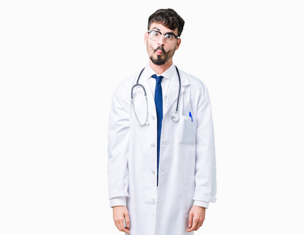 Młody lekarz człowiek sobie Szpital płaszcz na białym tle co ryby twarzy z warg, szalony i komiczny gest. Wyrażenie zabawny. - Zdjęcie, obraz