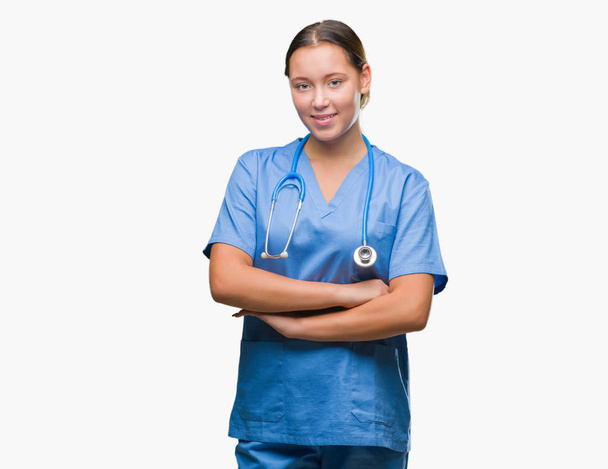 上医療制服を着て若い白人医師女性は分離幸せそうな顔で笑顔組んだ腕のカメラを見て背景です。肯定的な人. - 写真・画像